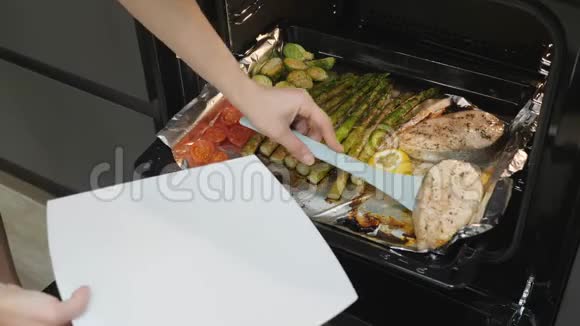 女人把鱼从烤箱里弄出来电烤箱里煮好的三文鱼牛排和蔬菜准备晚餐健康饮食烤牛肉视频的预览图
