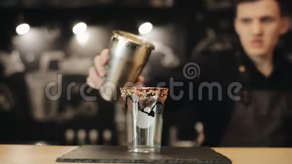 男调酒师用手把奶昔倒入一个外卖杯中上面有一些巧克力和糖果调料视频的预览图
