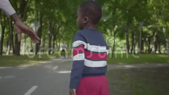在公园里一位不可辨认的非洲裔美国妇女与小儿子男孩和妈妈携手漫步可爱视频的预览图