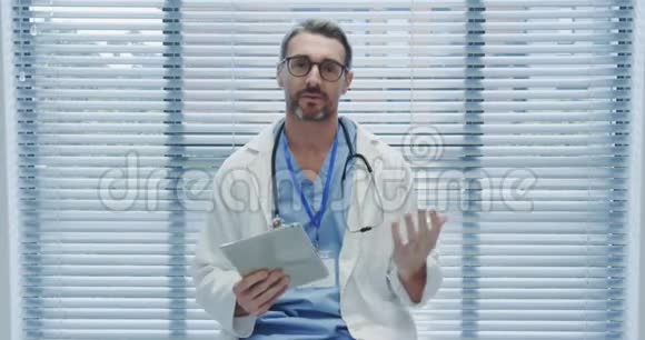 中年男性医生使用平板电脑并与4k摄像机通话视频的预览图