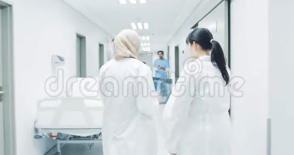 医院走廊上的医生通过保健工作者帮助老年病人4k视频的预览图