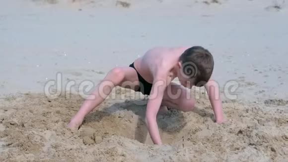 小男孩在海沙滩上玩挖铲子深洞扔沙子视频的预览图