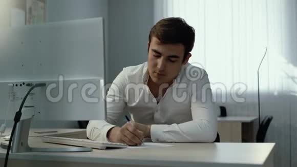 年轻商人使用台式电脑在记事本上写下信息视频的预览图