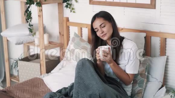 性感女孩坐在床上喝咖啡放松和微笑慢动作视频的预览图