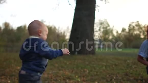 快乐的孩子在秋天公园里和一只狗玩旁边是他幸福的妈妈儿童情绪视频的预览图