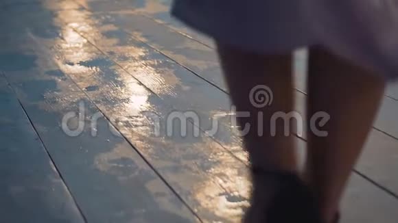 穿鞋的女孩在一个潮湿的码头上拍得不错相机看着她的腿然后上升视频的预览图