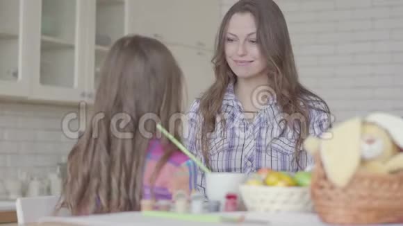 年轻的妈妈和可爱的女孩在厨房聊天那孩子用小手摸妈妈的脸友好视频的预览图