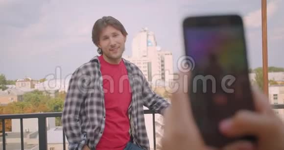 一位成年白人快乐男子的特写镜头他的女朋友站在阳台上通过电话拍照视频的预览图