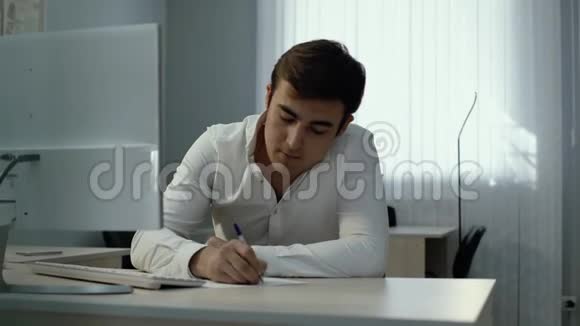办公室工作人员在无线键盘上打字并用钢笔在笔记本上写字视频的预览图