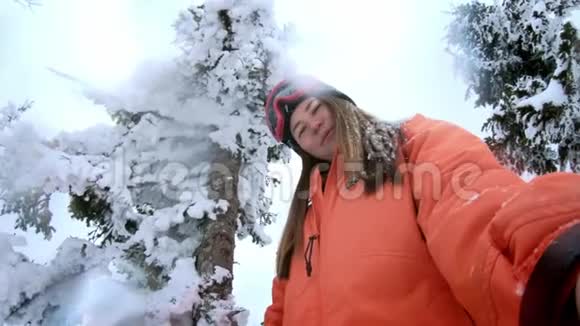 一个美丽的女孩在冬天森林里的自拍他头上一棵圣诞树上落下的雪冬天的乐趣视频的预览图