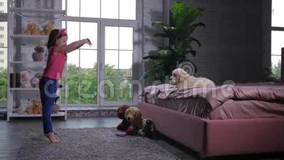 可爱的小女孩为躺在床上的小狗跳舞视频的预览图