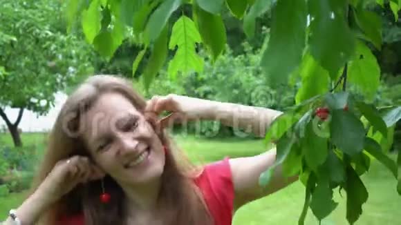 嬉戏的女人在花园里摆着天然樱桃浆果耳环万向节运动视频的预览图
