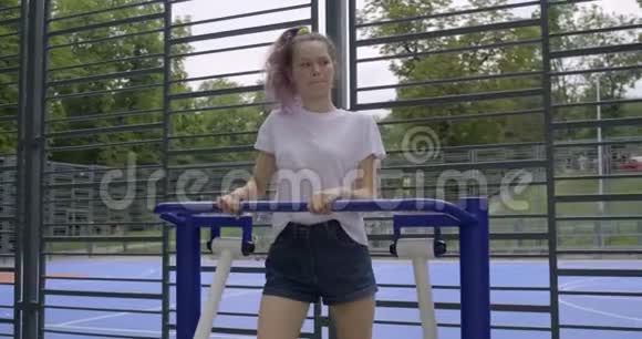 青少年女孩在户外运动模拟器上做腿部运动视频的预览图