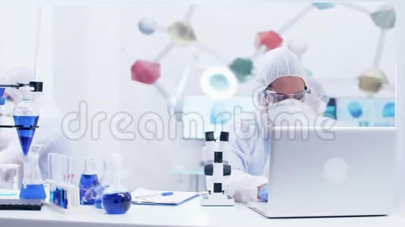 女科学家穿着防护装备透过显微镜观察视频的预览图