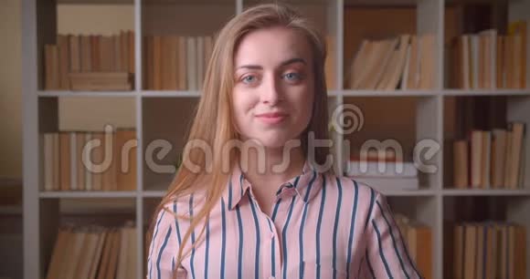 年轻漂亮的白种人女学生的特写照片她竖起大拇指微笑着看着学院里的摄像机视频的预览图