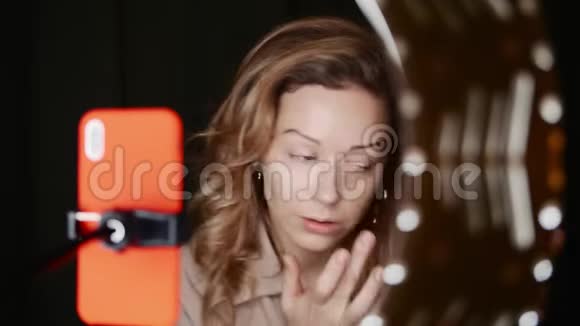 漂亮的金发女人美女vlogger在灯光下化妆视频的预览图