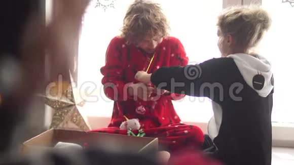 卷曲的孩子们一个男孩和一个女孩从盒子里拿出圣诞玩具球和一颗星星圣诞节准备视频的预览图