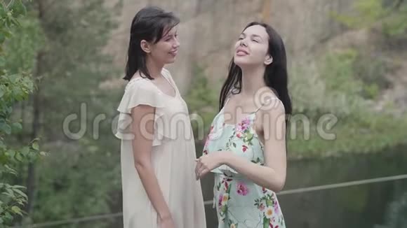 两个穿着白色短裙的漂亮女人站在大自然的周围望着天空壮观的景色慢慢视频的预览图