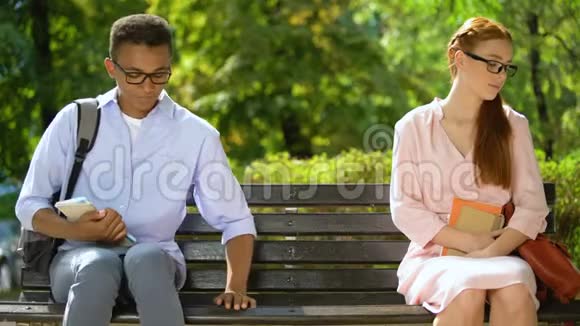 戴着眼镜的有趣的青少年坐在长凳上彼此靠近视频的预览图