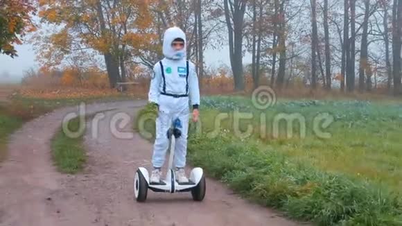 一个穿着宇航员服装的男孩骑着陀螺仪穿过秋天的森林视频的预览图