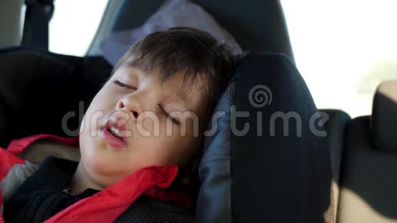穿红色夹克的小孩睡在一辆站立的车里视频的预览图