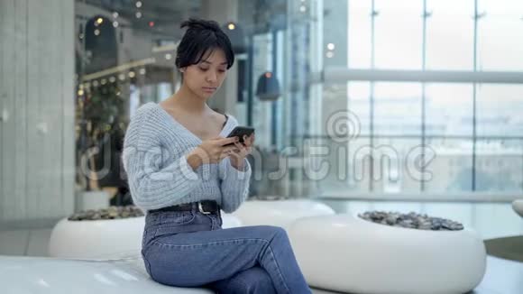 坐在购物中心休息区发短信的亚洲少女中锋视频的预览图