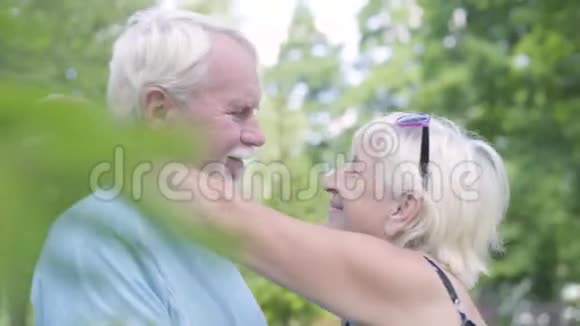 积极的成熟夫妇亲吻和看着镜头微笑年长的女人拥抱她的丈夫可爱的幸福家庭视频的预览图