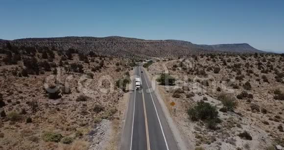 在炎热的夏天美国亚利桑那州Drone在沿着美丽的砂岩沙漠山路行驶的大型送货卡车上倾斜下来视频的预览图