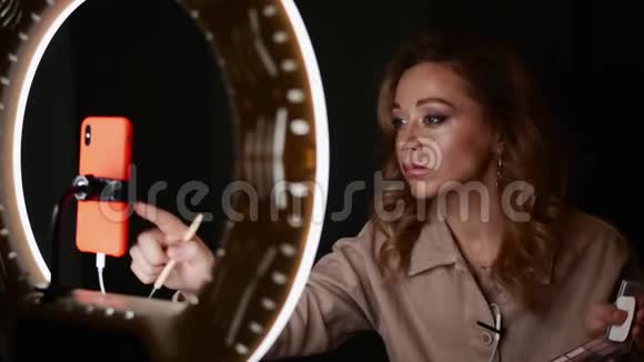 化妆师年轻漂亮的女人使用智能手机连接到环形灯视频的预览图