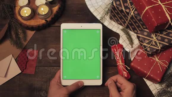 木制桌上全新白色平板电脑的手点击和滑动右垂直绿色屏幕的顶部视图视频的预览图