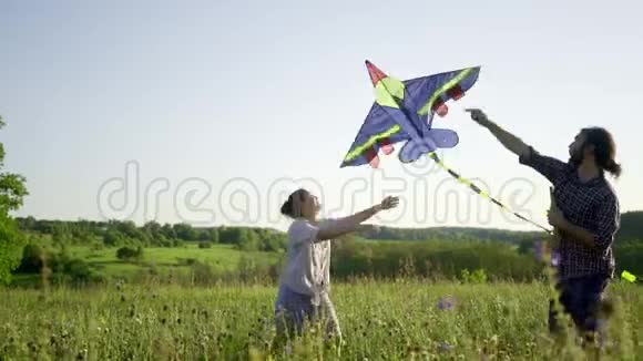 一对年轻快乐的情侣在夏天的田野里放风筝视频的预览图