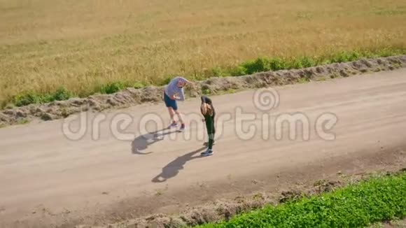 一个年轻人和一个穿着运动服的女孩子在沿着碎石路慢跑之前正在身体视频的预览图