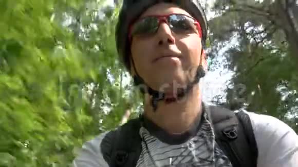 戴着头盔和太阳镜的职业自行车手在公园里骑车视频的预览图