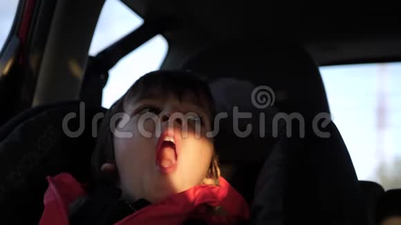穿红色夹克的小孩睡在一辆站立的车里视频的预览图