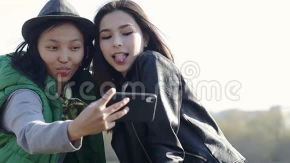 两个美丽的亚洲少女正在拍一张滑稽的自拍视频的预览图