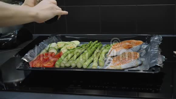 厨师调味新鲜蔬菜和鳟鱼三文鱼加香料胡椒和盐然后在烤箱里煮视频的预览图