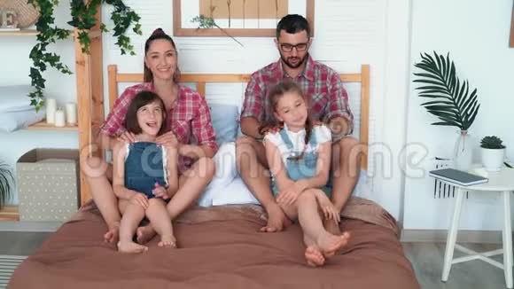 父母为两个女儿做按摩坐在床上开怀大笑视频的预览图