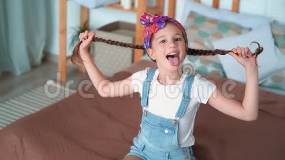 欢快的女孩在长辫子上玩耍的肖像露出舌头动作缓慢视频的预览图