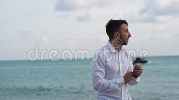 站在海边的快乐胡子男的肖像年轻人安详地站在海滨视频的预览图