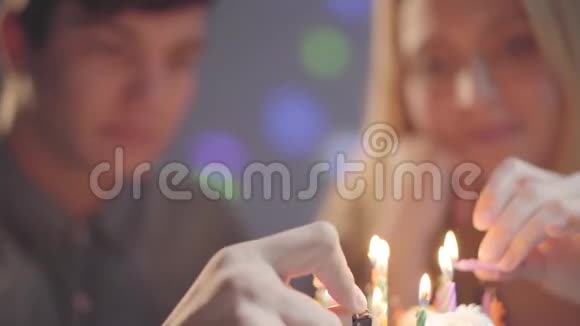 模糊的女孩和一个男人坐在小蛋糕前面用打火机点燃蜡烛他过生日视频的预览图