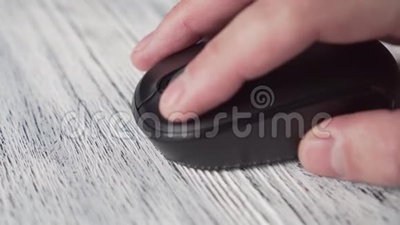 一个年轻人用一只黑色的无线电脑鼠标把手指按在白色木制纹理桌子上的钥匙上视频的预览图