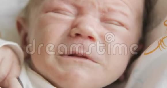 睡意朦胧悲伤的新生儿闭着眼睛在床上哭泣视频的预览图