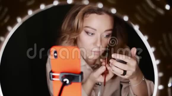 漂亮的女化妆师将眼线放在眼圈灯光前视频的预览图
