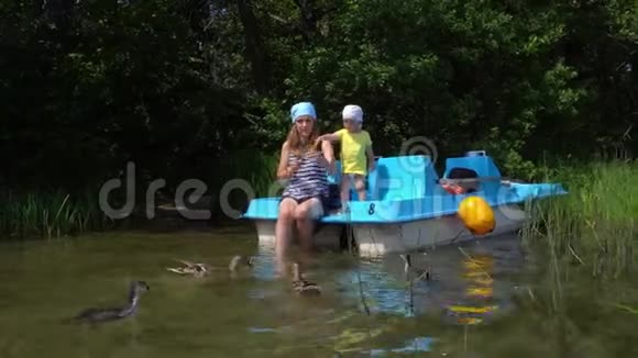 妈妈和小儿子一起喂鸭子鸟儿坐在双体船上万向节运动视频的预览图