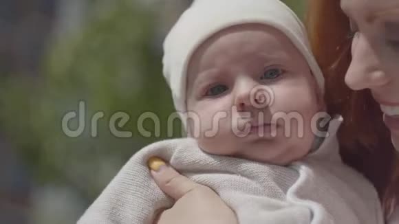 肖像漂亮的红发女人抱着婴儿在院子里的特写镜头微笑享受阳光的女士视频的预览图