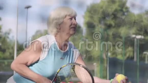 成熟集中的女人拿着球拍和球就要经过网球场户外休闲活动射击视频的预览图