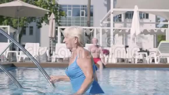 幸福的成熟夫妇一起在酒店的游泳池里放松漂亮的老太太晒太阳出来了视频的预览图