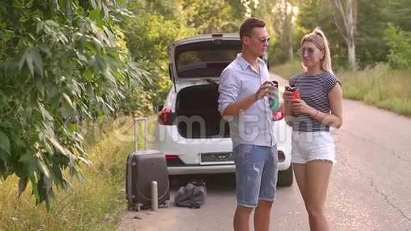 夏天的汽车旅行中一对夫妇在路边喝咖啡放松视频的预览图