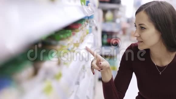 女人的肖像看着价格标签在超市里寻找货架上的产品视频的预览图
