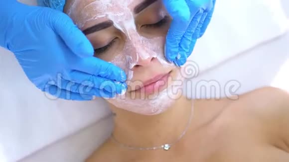 专业美容师和皮肤科医生在女性面部涂面膜并做面部按摩紧致蛋白的处理方法视频的预览图
